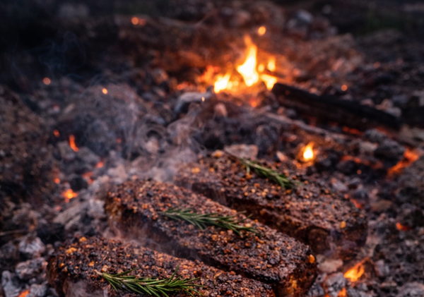 Steaks being grilled over an open flame on a grill.